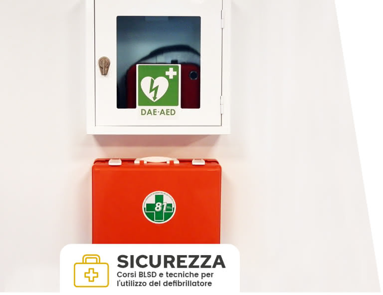 Un defibrillatore automatico esterno (DAE-AED) in una parete bianca, con il kit di emergenza ben visibile sotto, in un ambiente aziendale sicuro.